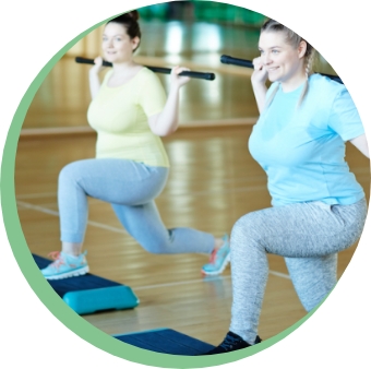 Two women participating in a group fitness class and enjoying themselves